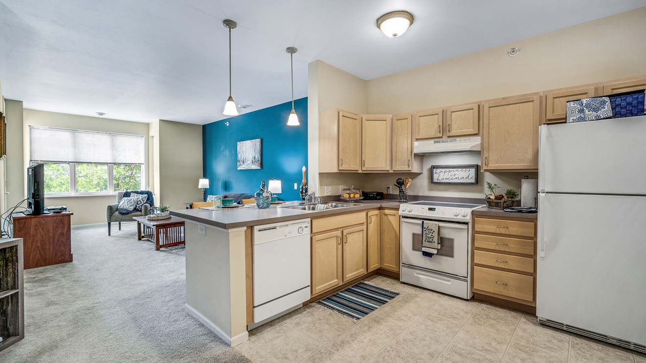 Holiday Village at the Falls independent living apartment with kitchen appliances and living room with accent wall.